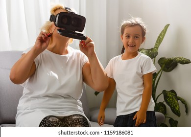 A young girl explains to an elderly woman how to use virtual reality glasses. The older generation and new technologies. - Powered by Shutterstock