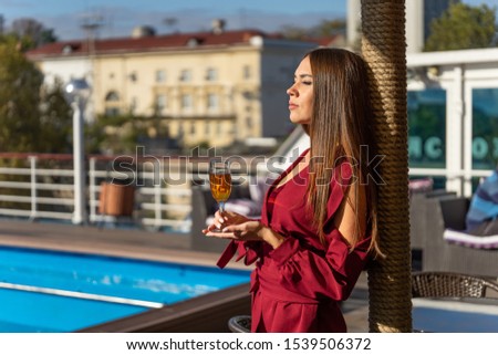 Young girl with eyes closed with pleasure drinking wine on a cruise ship close to the pool