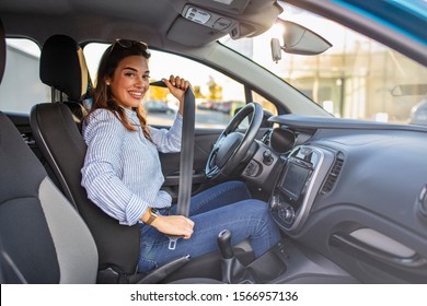 Young girl is fastening her seat belt. Photo of a business woman sitting in a car putting on her seat belt.  Woman fastening seat belt in the car, safety concept 