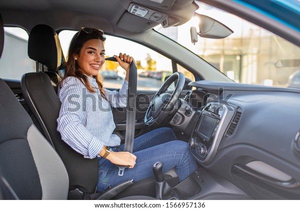 Young girl is fastening her seat\
belt. Photo of a business woman sitting in a car putting on her\
seat belt.  Woman fastening seat belt in the car, safety concept\
