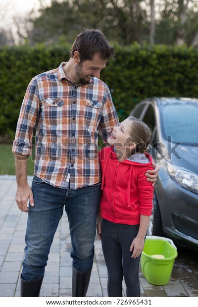 Young\
girl and father hugging each other near the\
car