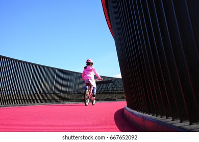 Young girl (female age 07) rides a bike on bright pink Nelson street cycleway in Auckland, New Zealand. Real people. Copy space.