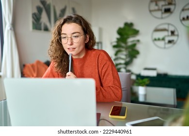 Young girl female student using laptop elearning or remote working at home office looking at computer watching webinar, learning training, studying online seminar or video calling for work meeting. - Powered by Shutterstock