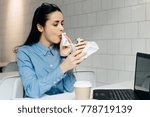 young girl freelancer eagerly eats a sandwich while working on a laptop