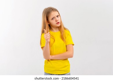 Young Girl Frowns And Looks Very Dissatisfied, Shake Forefinger Telling No Way, Scolding Or Telling Off Someone, Dont Give Permission, Wears Yellow Tshirt, Stands Over White Background