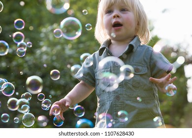 Young Girl In Garden Chasing Bubbles