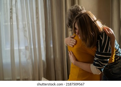 A young girl gently hugs her elderly mother or grandmother, visits her and supports in her cozy home, daughter takes care and congratulates her relative on the holiday.  - Powered by Shutterstock