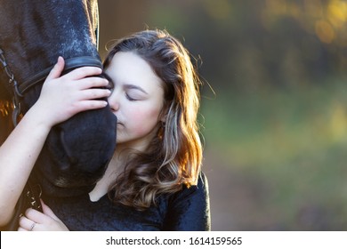 young girl gently kisses black horse autumn forest sunset - Powered by Shutterstock