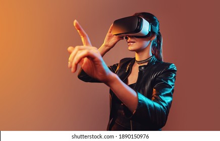 Young girl getting experience VR headset is using augmented reality eyeglasses being in virtual reality. Girl with hands up wearing virtual reality goggles. Woman touching air during VR experience - Powered by Shutterstock