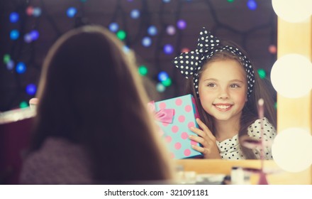 Young Girl With Gift Sitting Mear A Mirror.