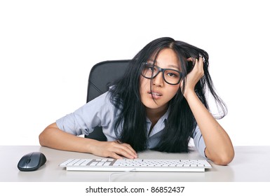 A young girl with glasses on looking stressed out sitting a desk with a keyboard and mouse