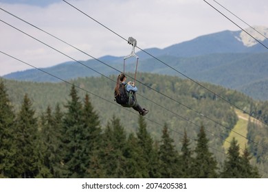 A Young Girl Goes Down The Zipline And Takes A Selfie With An Action Camera. Day, Summer, Mountains.