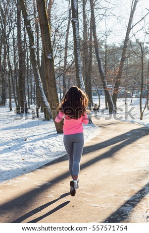 Young girl goes in for sports in winter park. Jogging training.