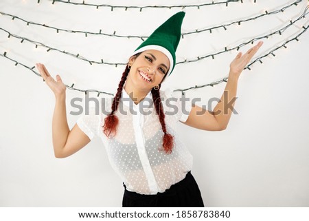 Young girl with green Christmas hat and braids in her red hair very happy smiling and raising her arms