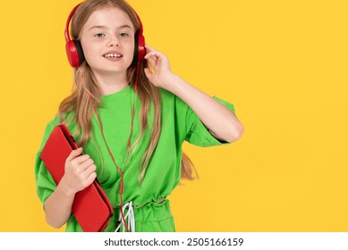 Young girl in green t-shirt listening to music enjoying music in red headphones on yellow background and holding tablet - Powered by Shutterstock