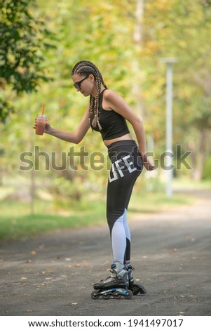 Young girl with hair braids learning to ride on roller skates and how to keep balance