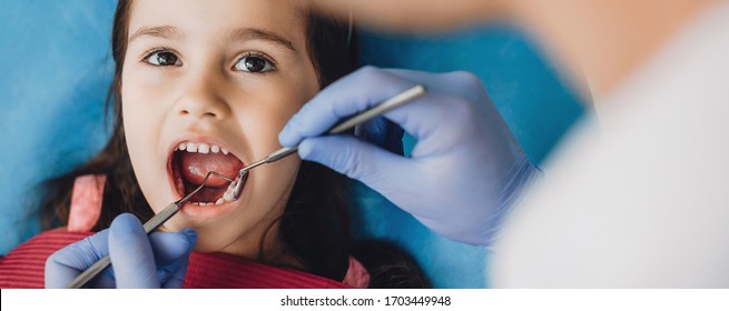 Young Girl Having An Examination At The Dentist Is Looking At Him Working Using Special Tools