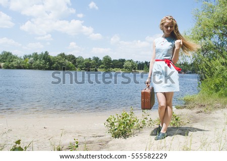 Young girl having fun on the beach with suitcase. Summer vacation and travel concept 