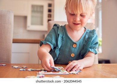 Young Girl Having Fun Sitting At Table At Home Doing Jigsaw Puzzle - Powered by Shutterstock