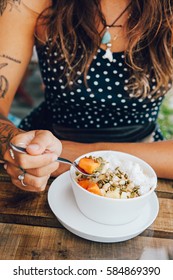 Young Girl Having A Good Morning Healthy Breakfast Smoothie Bowl Made Of Super Foods, Fruits, Nuts, Berries, Granola, Shredded Coconut, Acai