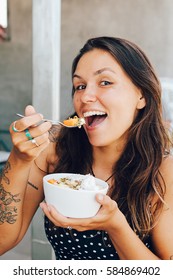 Young Girl Having A Good Morning Healthy Breakfast Smoothie Bowl Made Of Super Foods, Fruits, Nuts, Berries, Granola, Shredded Coconut, Acai