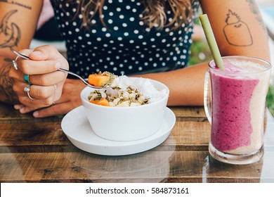 Young Girl Having A Good Morning Healthy Breakfast Smoothie Bowl  And A Drink Made Of Super Foods, Fruits, Nuts, Berries, Granola, Shredded Coconut, Acai