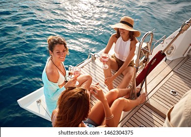 young friend’s girl having party on sailing boat and drinking wine at summer day
