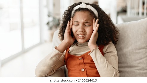 Young girl, headache and sofa with stress in anxiety, pain or distress for noise at home. Little female person, child or kid alone with migraine on living room or lounge couch in fatigue or burnout - Powered by Shutterstock