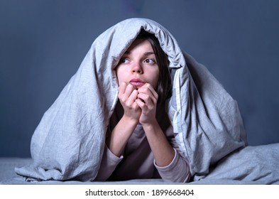 Young girl hid under a blanket from all problems, procrastinating, millennials generation. Woman covered with a blanket and is worried about insomnia, poor sleep, getting stress. - Shutterstock ID 1899668404
