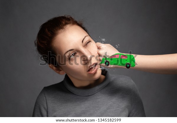a young girl\
is hit in the face with a fist that represents a car .the concept\
of accidents and insured\
events