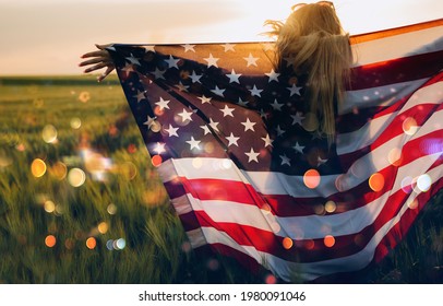 Young girl holding Bengal fire with American flag at sunset. America celebrate 4th of July. Independence Day.	