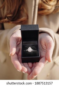 A Young Girl Is Holding A Black Box With A Pear-shaped Diamond Engagement Ring. A Romantic Marriage Proposal.