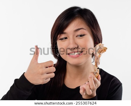 Young girl holding, eating fried chicken