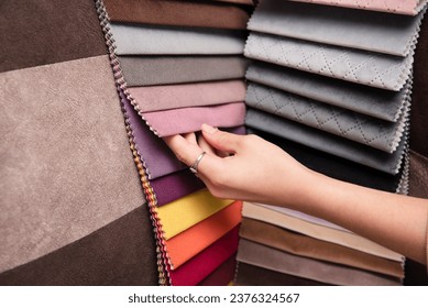 A young girl is holding a fabric catalog for choosing fabric for upholstered furniture, the girl has chosen a pink fabric for her new sofa and wants to paint the walls pink - Powered by Shutterstock