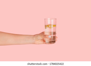 Young girl holding glass of infused water with lemon on pink background, closeup view - Powered by Shutterstock