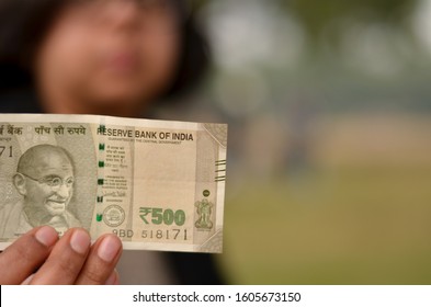 A Young Girl Holding A New Green 500 Rs Indian Currency Note In Her Hand Issued After Demonetisation In A Park With A Green Background Pointing To Reserve Bank Of India Written On The Note