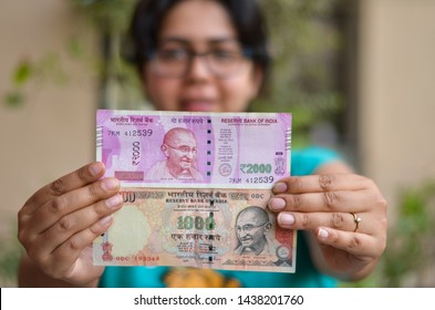 A Young Girl Holding Old 1000 And New Pink 2000 Denomination Indian Rupees Currency Note With Hands Stretched After Demonetisation In Background