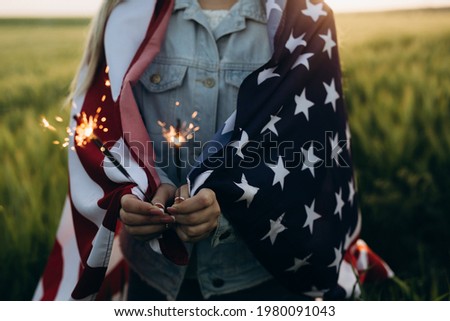 Young girl holding Sparklers with American flag at sunset. America celebrate 4th of July. Independence Day.	