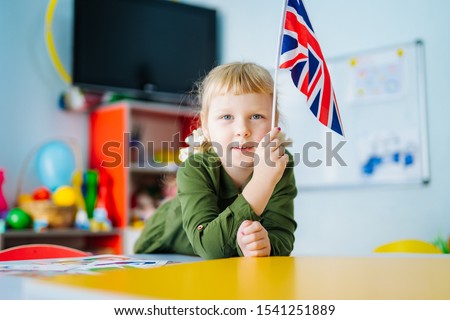 Young girl is holding Union Jack flag. British flag on the front view. Blurred background. Closeup.