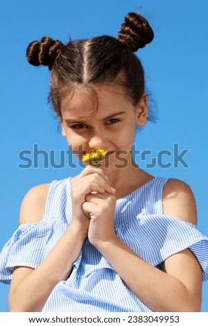 A young girl holds a delicate flower in her hand, showcasing the beauty of nature. This image can be used to depict innocence, love, or the joy of discovery. It is suitable for various projects and de