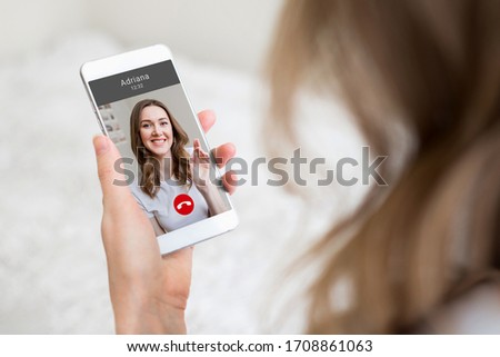 A young girl holds a mobile phone in hand and talking to her girlfriend on video chat, video calls, conference