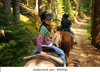 Young Girl Horseback Riding Along Forest Trail.