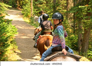 Young Girl Horseback Riding Along Forest Trail.