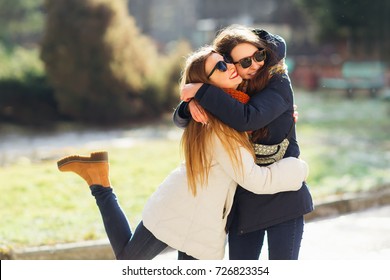 Young girl hugging her older sister smiling. Two long haired best friends having the best time of their lives.