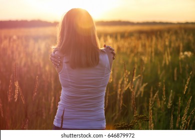 Young girl hugging herself on a sunny field. Instagram