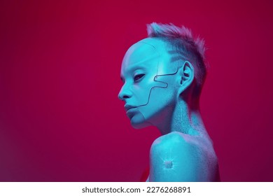 Young girl in image of futuristic cyborg robot with bare shoulders against pink studio background in neon light. Digitalization. Cyberpunk style. Concept of futurism, surrealism, digital world, robot