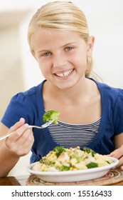 Young Girl Indoors Eating Pasta With Brocoli Smiling