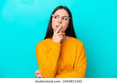 Young girl isolated on blue background With glasses and having doubts - Powered by Shutterstock