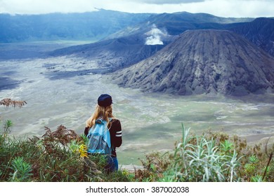 Young Girl In Jacket A Baseball Cap With A Backpack, Traveling The World, Stands On A Hill And Looks At The Volcano, Beautiful Scenery, New Discoveries, Emotions, Outdoor Portrait, Close Up, Turist