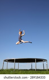 Young girl jumping on a trampoline on green meadow - Shutterstock ID 289184333